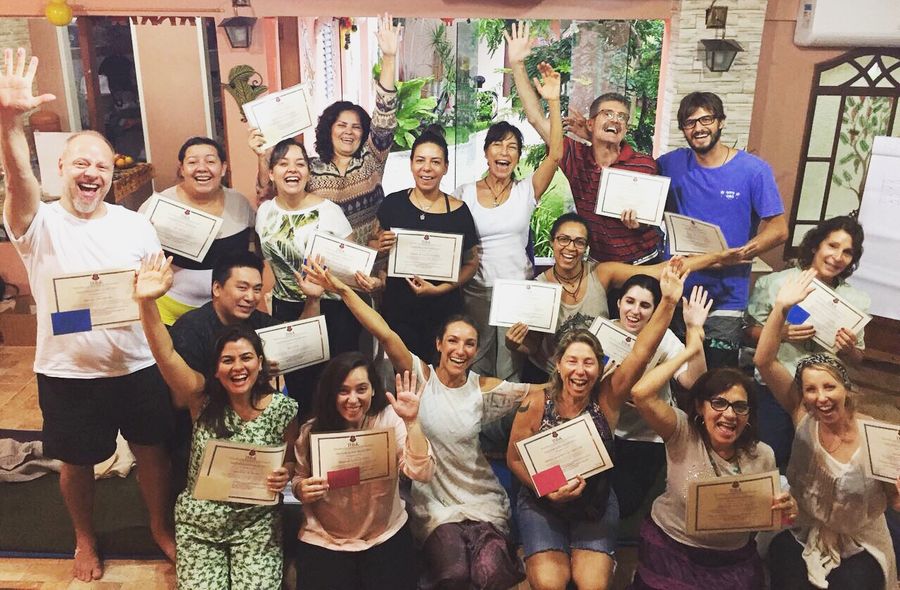 Uma turma de ThetaHealing com os braços para cima, segurando seus certificados